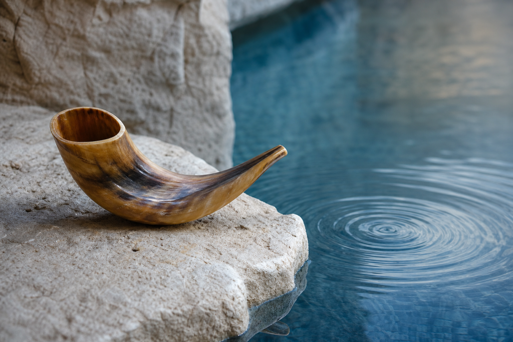 A shofar beside still water symbolizing reflection and return during Elul